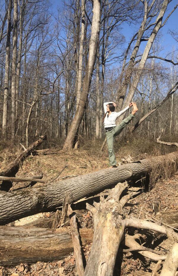 A person standing on one leg in the woods