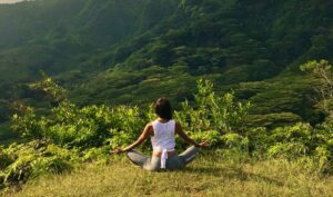 A woman sitting in the grass with her legs crossed.