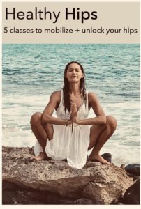 A woman sitting on the beach in front of water.