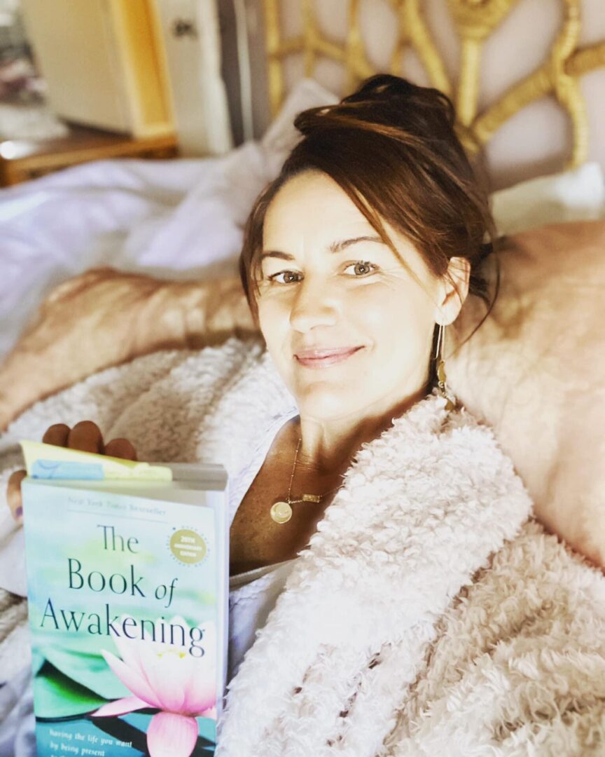 A woman laying in bed holding an open book.